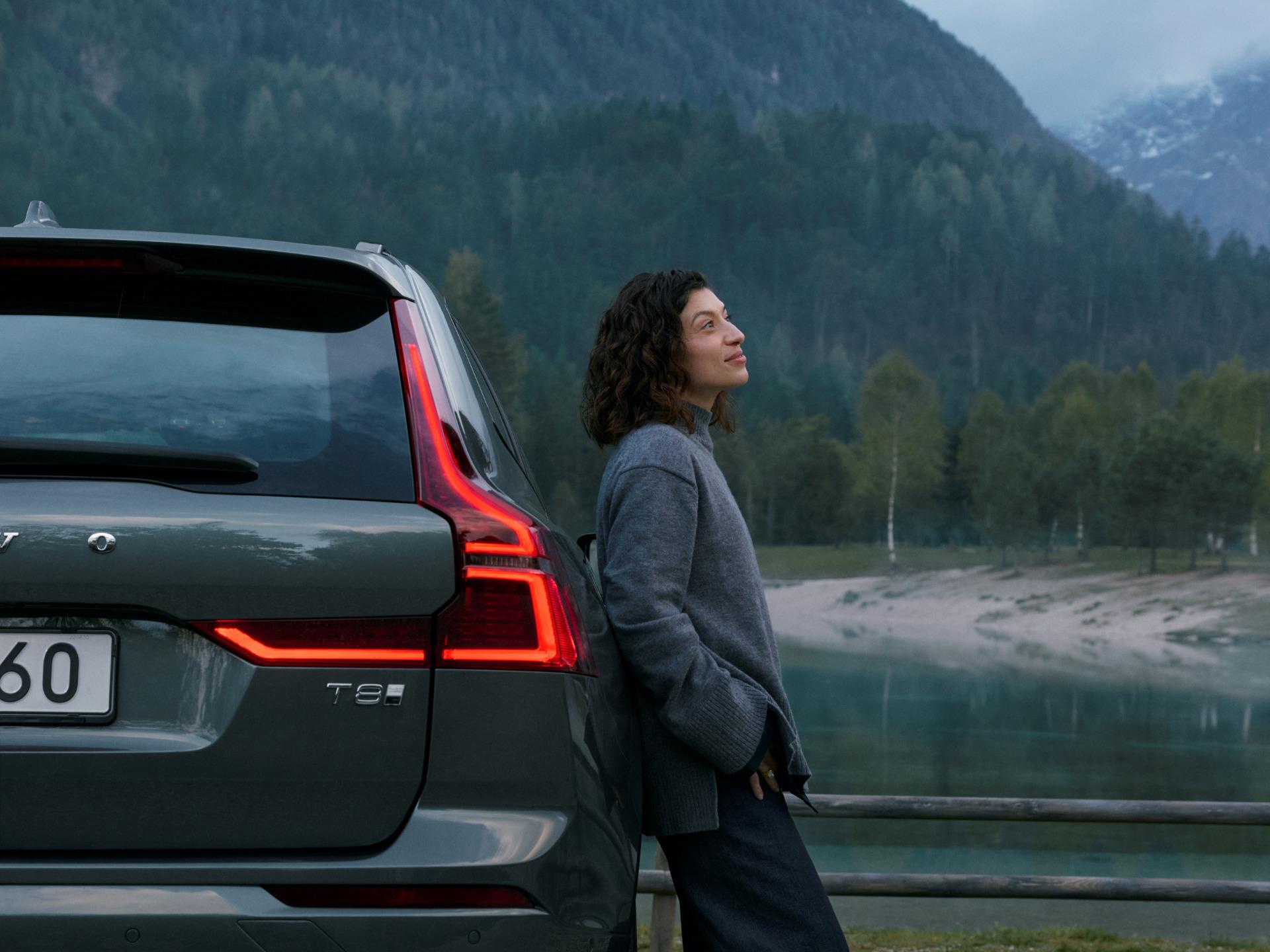Mujer admirando el paisaje en la parte trasera de un Volvo SUV estacionado, en un entorno natural.