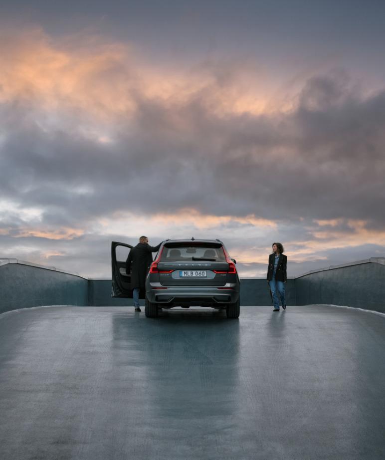 Camioneta Volvo gris estacionado con dos personas al atardecer.